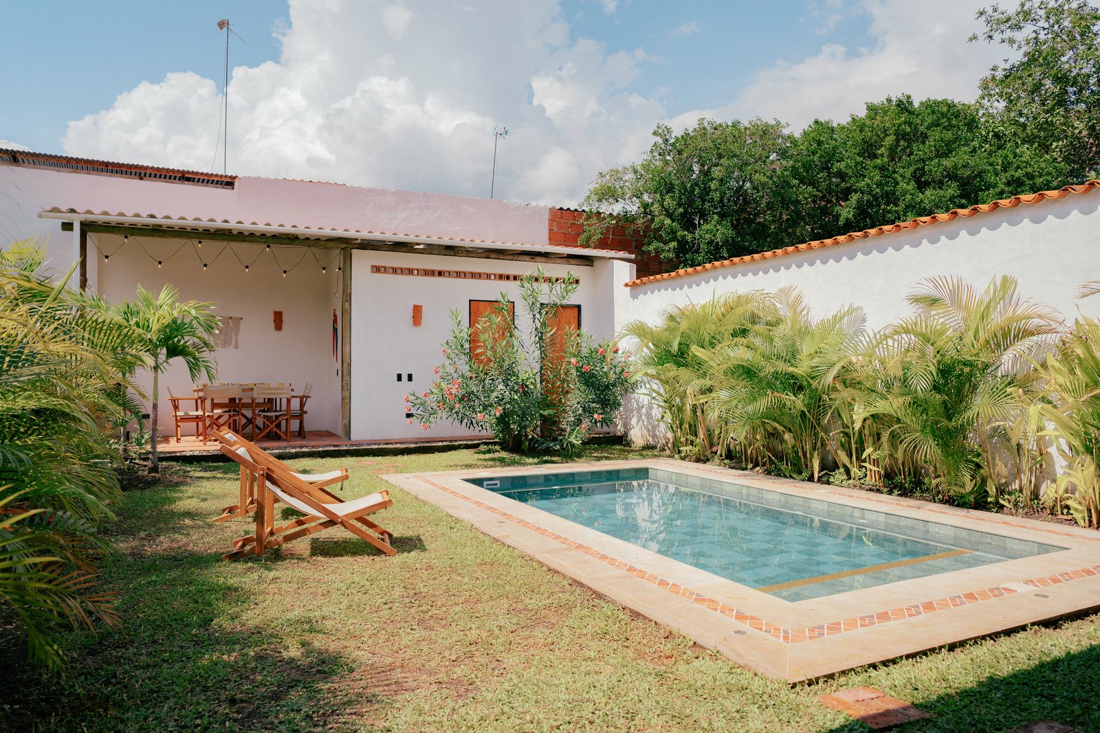 Jardín de Casa UIRA con la piscina y la casa de tejas de barro al fondo