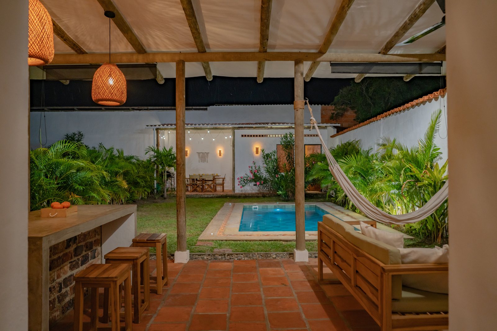 Terraza techada con hamaca y barra de madera con vista a la piscina