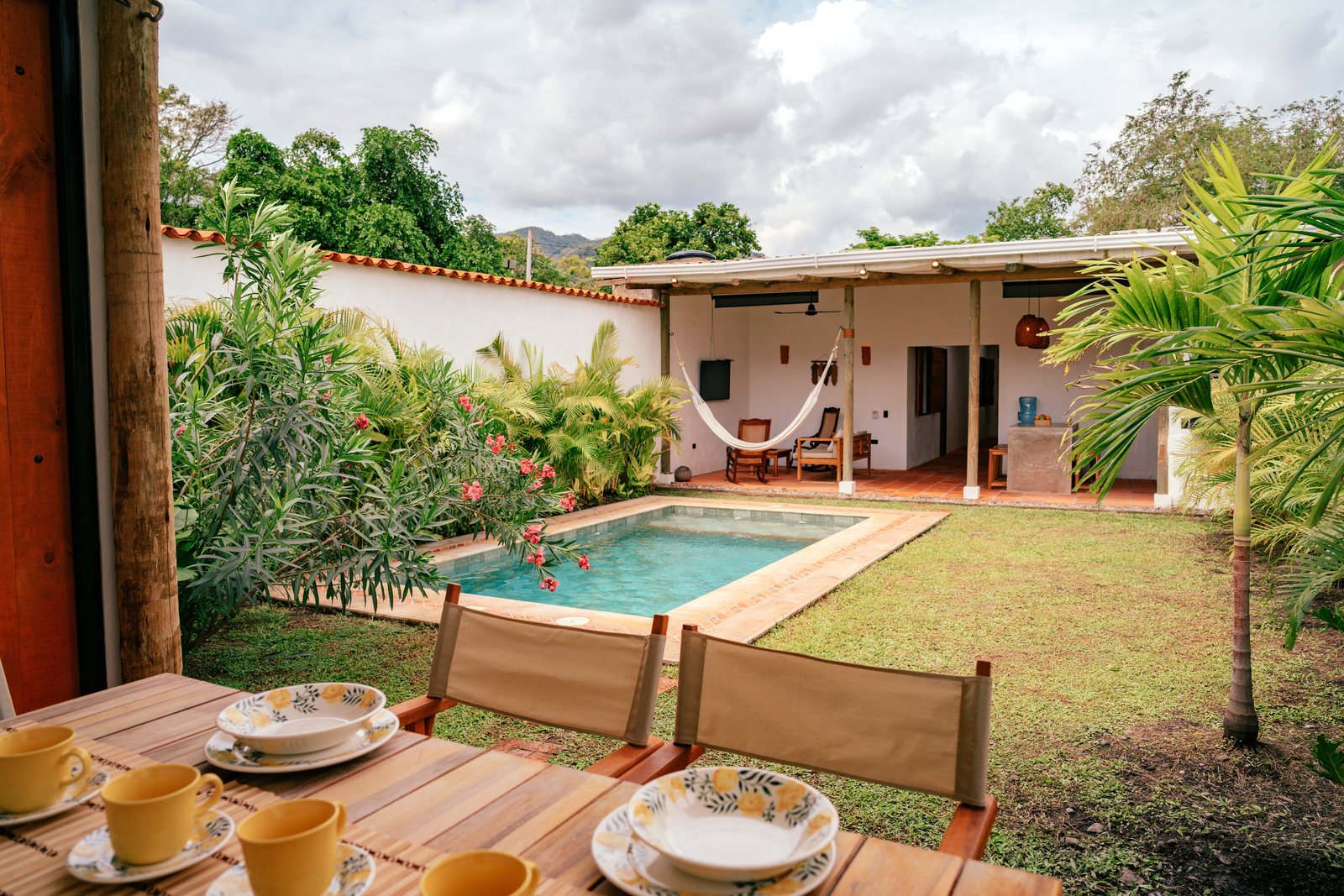 Mesa servida para el desayuno con vista a la piscina y al jardín de la casa