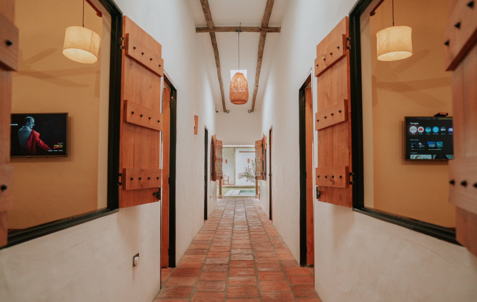 Pasillo con puertas de madera hacia las habitaciones, cada una con su Smart TV