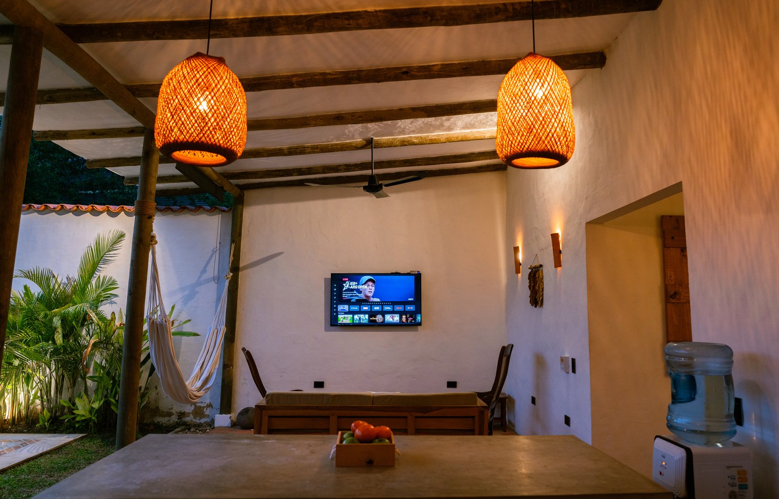 Sala de estar con lámparas de mimbre, Smart TV y techo de vigas de madera
